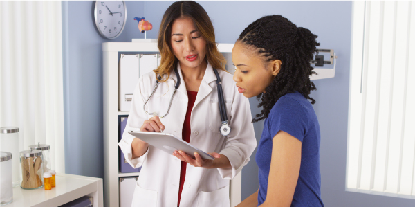 Image of a female doctor reading a chart to an adult female patient