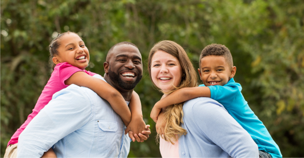 Family picture, husband, wife, young boy and girl smiling while walking in the park